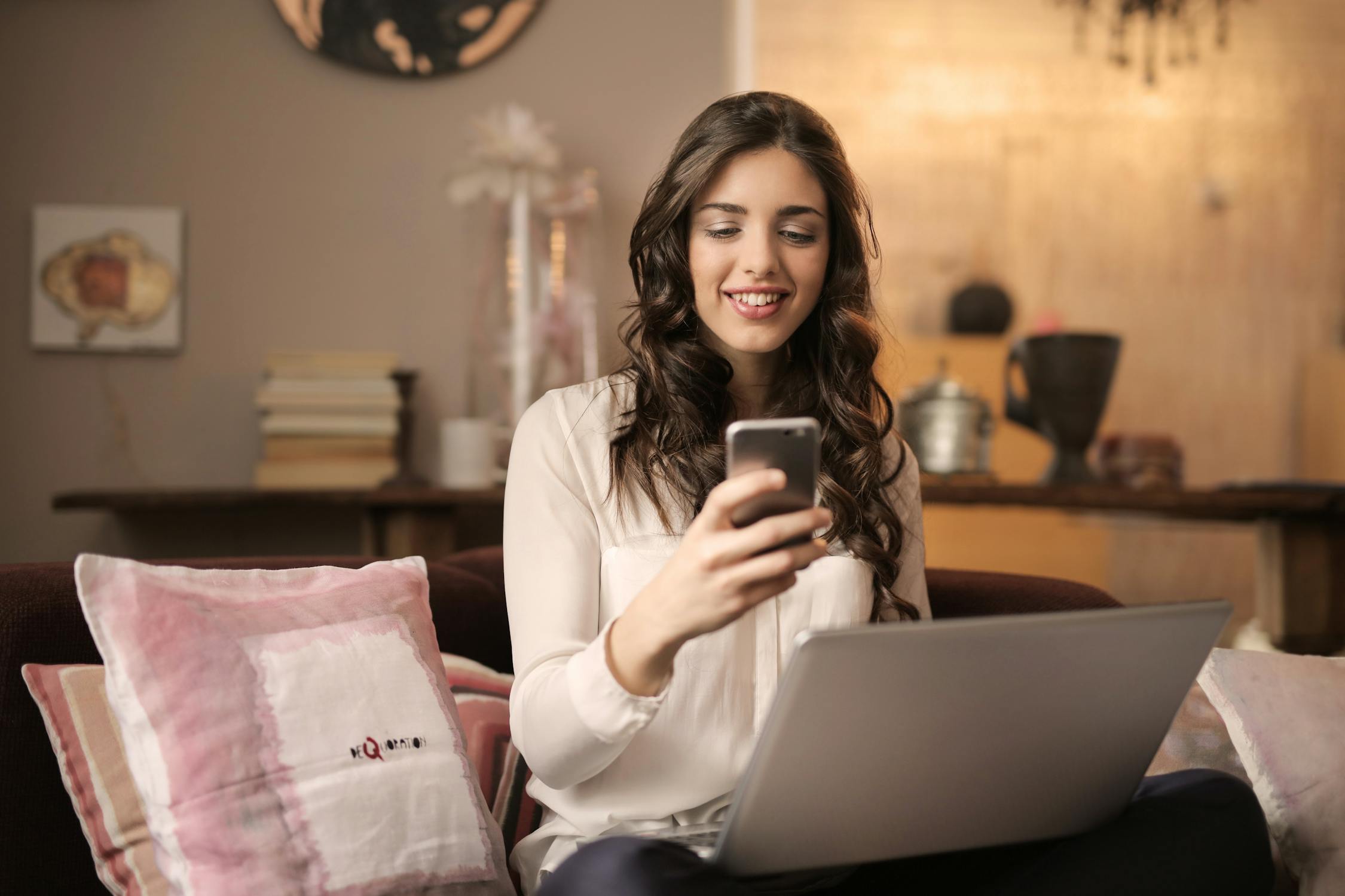 Woman on sofa booking an appointment on her phone