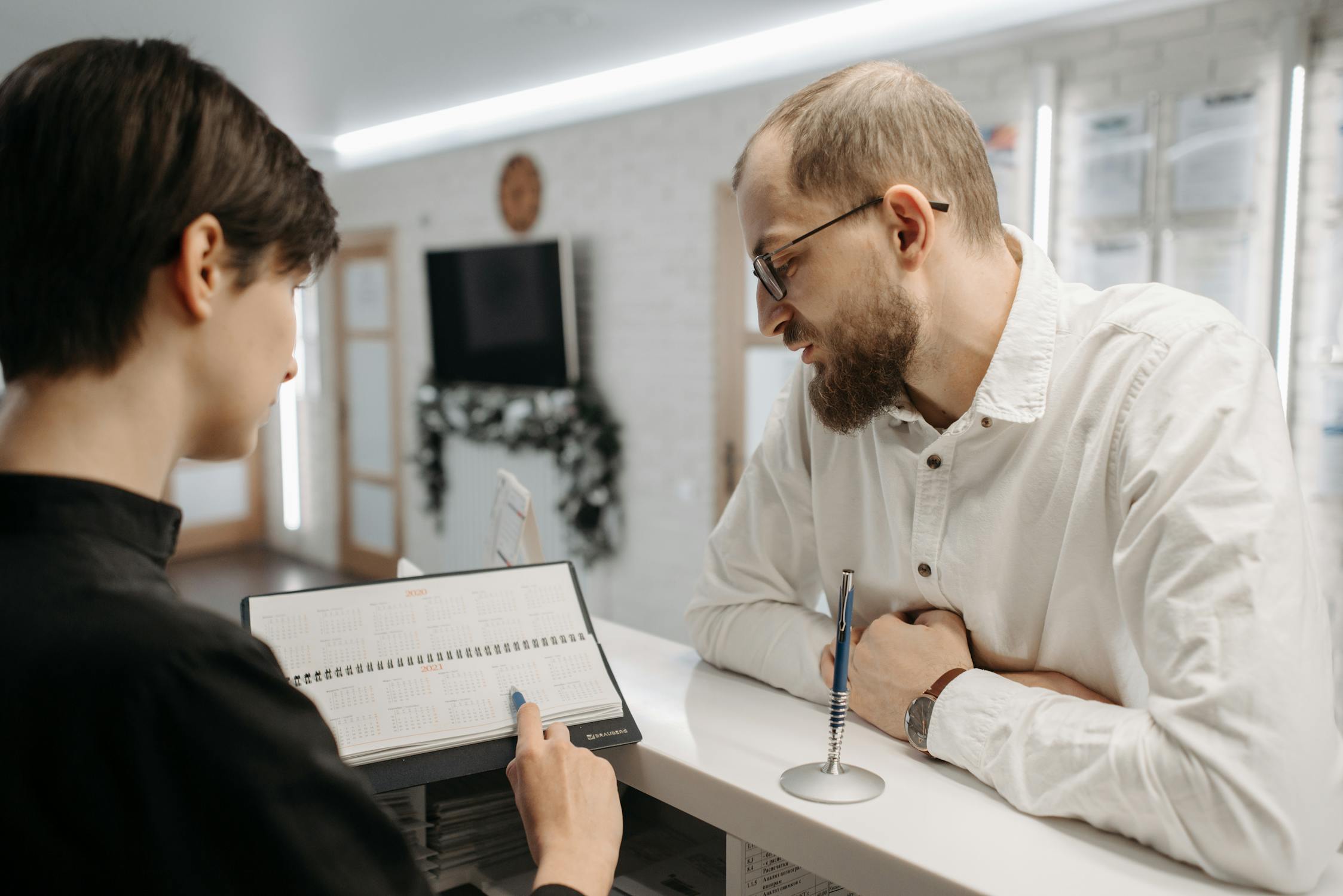Receptionist showing appointment calendar to a client