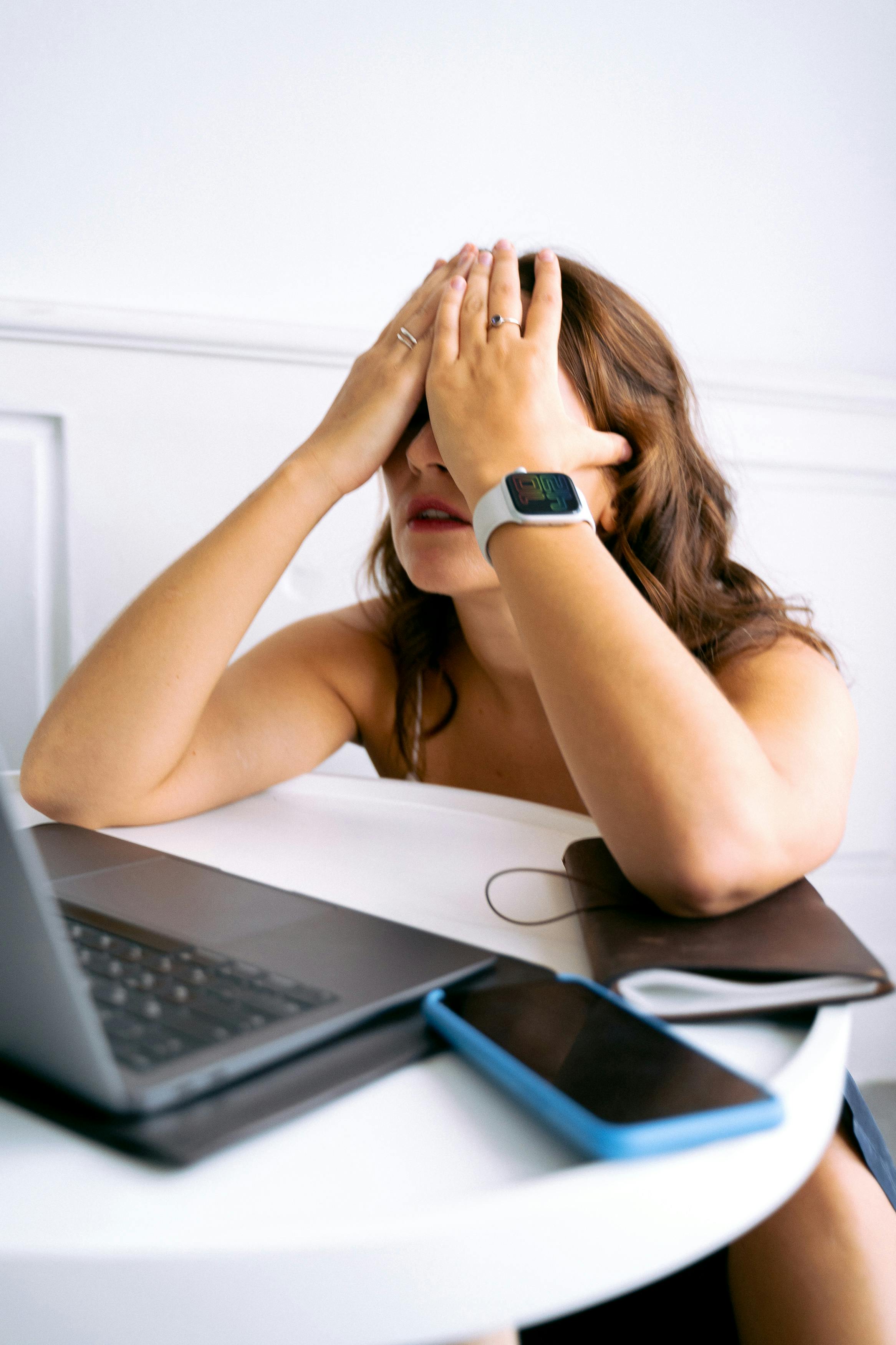 Overwhelmed business owner with head in hands at her desk